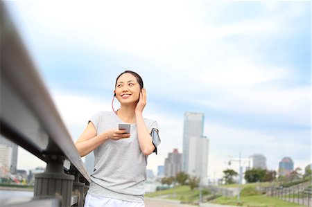 Attractive Japanese woman listening to music by a river downtown Tokyo, Japan Stock Photo - Premium Royalty-Free, Code: 622-08839861