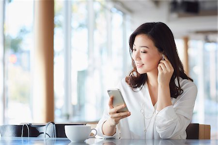 Japanese woman with smartphone in a stylish cafe Stock Photo - Premium Royalty-Free, Code: 622-09014297