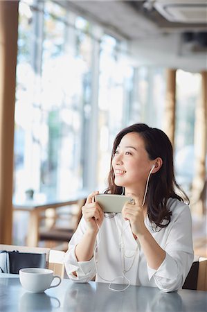 Japanese woman with smartphone in a stylish cafe Stock Photo - Premium Royalty-Free, Code: 622-09014298