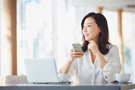 pc store - Japanese woman with smartphone in a stylish cafe Stock Photo - Premium Royalty-Free, Code: 622-09014307