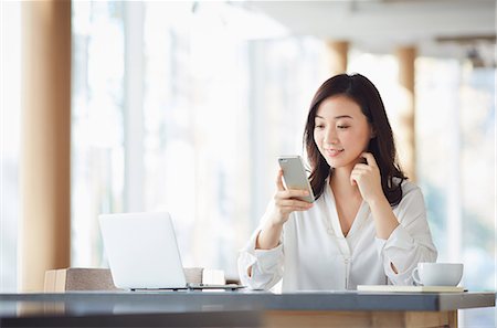 Japanese woman with smartphone in a stylish cafe Stock Photo - Premium Royalty-Free, Code: 622-09014312