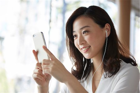 Japanese woman with smartphone in a stylish cafe Stock Photo - Premium Royalty-Free, Code: 622-09014660