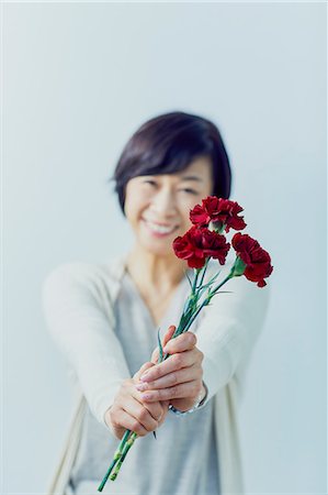 Japanese senior woman holding red roses Stock Photo - Premium Royalty-Free, Code: 622-09138754