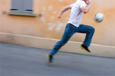 dribbler - Homme courir avec le ballon de football dans la rue Photographie de stock - Premium Libres de Droits, Code: 622-00701570