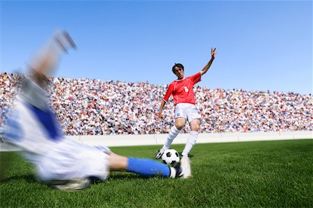 soccer slide - Soccer player kicking ball as defender slides in Stock Photo - Premium Royalty-Free, Code: 622-00701618