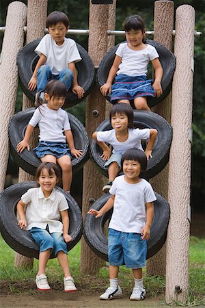 denim skirt - Smiling children sitting on tires climbing frame in park Stock Photo - Premium Royalty-Free, Code: 622-02354167