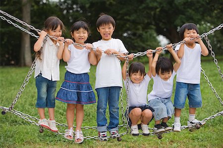 Smiling children standing on jungle gym Stock Photo - Premium Royalty-Free, Code: 622-02354171