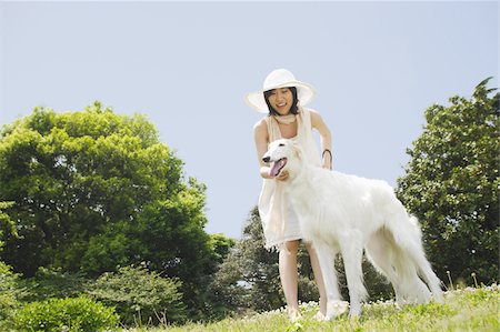 Smiling young woman with white dog in park Stock Photo - Premium Royalty-Free, Code: 622-02395509