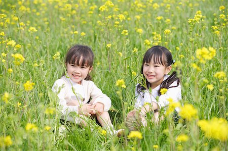 Two cute girls enjoying sitting together in  mustard field Foto de stock - Sin royalties Premium, Código: 622-02395726