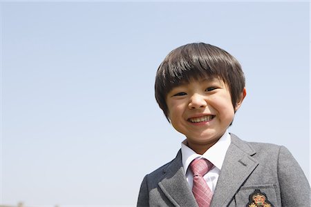 Japanese schoolboy smiling against clear sky Stock Photo - Premium Royalty-Free, Code: 622-02758464