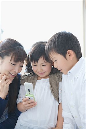 Asian mother and her children looking on cellphone Stock Photo - Premium Royalty-Free, Code: 622-02759159