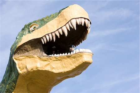 Statue of Dinosaur with Open Mouth against Blue Sky Fotografie stock - Premium Royalty-Free, Codice: 622-02759612