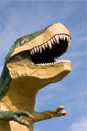 Statue of Dinosaur with Open Mouth against Blue Sky Fotografie stock - Premium Royalty-Free, Codice: 622-02759613