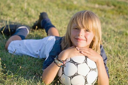 Boy smiling and lying on grass with soccer ball Stock Photo - Premium Royalty-Free, Code: 622-02913345