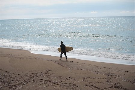 simsearch:673-02386382,k - Young man walking along shoreline with his surfboard Stock Photo - Premium Royalty-Free, Code: 622-02913425