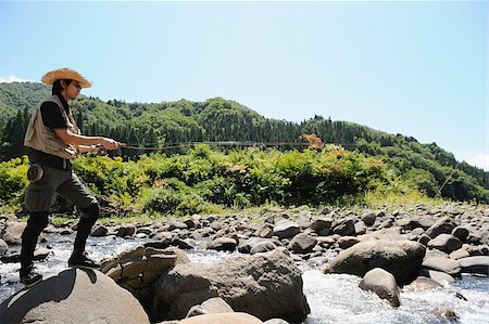 simsearch:622-02913456,k - Man with straw hat standing on stone and holding fishing rod Fotografie stock - Premium Royalty-Free, Codice: 622-02913457