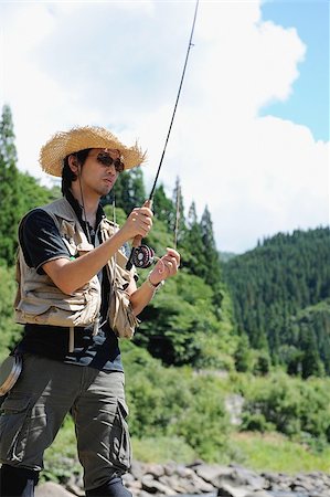 simsearch:622-02913459,k - Man with straw hat standing and holding fishing rod Fotografie stock - Premium Royalty-Free, Codice: 622-02913453