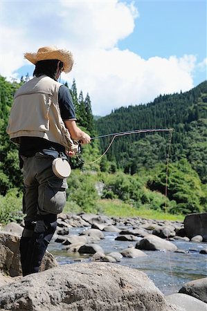 simsearch:622-02913459,k - Man with straw hat standing on stone and holding fishing rod Fotografie stock - Premium Royalty-Free, Codice: 622-02913468