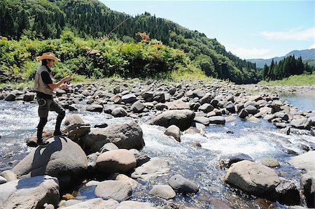 simsearch:622-02913459,k - Man with straw hat standing on stone and holding fishing rod Fotografie stock - Premium Royalty-Free, Codice: 622-02913463