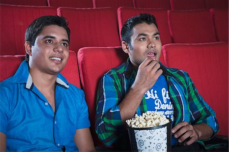 simsearch:630-06724559,k - Friends enjoying movie with popcorns in a cinema hall Foto de stock - Sin royalties Premium, Código: 630-06724487