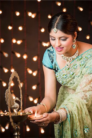 diwali pictures - Woman lighting oil lamps on Diwali Foto de stock - Sin royalties Premium, Código: 630-06724482