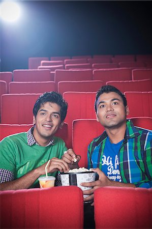 Friends enjoying movie with popcorns in a cinema hall Foto de stock - Sin royalties Premium, Código: 630-06724490