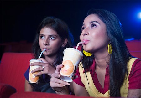 simsearch:630-06724559,k - Two female friends enjoying soft drinks while watching movie in a cinema hall Foto de stock - Sin royalties Premium, Código: 630-06724529