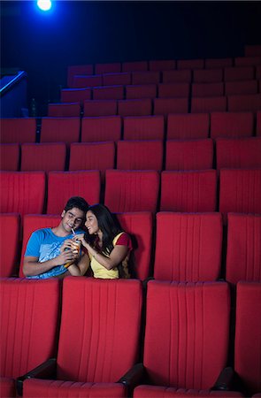 Couple enjoying soft drinks while watching movie in a cinema hall Stock Photo - Premium Royalty-Free, Code: 630-06724532
