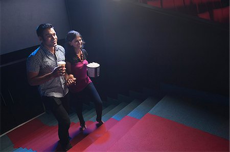 simsearch:632-06118179,k - Couple moving up on steps in a cinema hall Photographie de stock - Premium Libres de Droits, Code: 630-06724570