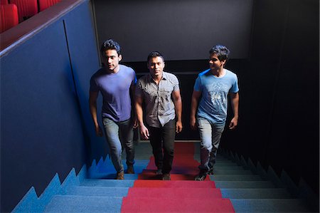 Three friends moving up on steps in a cinema hall Stock Photo - Premium Royalty-Free, Code: 630-06724572