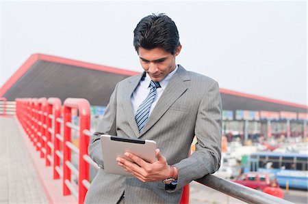 person on transit with tablet - Businessman using a digital tablet at footbridge, Gurgaon, Haryana, India Stock Photo - Premium Royalty-Free, Code: 630-06724614