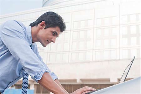 Businessman using a laptop outside an office building, Gurgaon, Haryana, India Stock Photo - Premium Royalty-Free, Code: 630-06724619