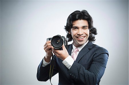 Businessman holding a digital SLR camera Stock Photo - Premium Royalty-Free, Code: 630-06724738