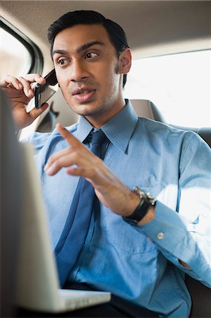 simsearch:6111-06728259,k - Bengali businessman using a laptop and talking on a mobile phone in a car Stock Photo - Premium Royalty-Free, Code: 630-06724894