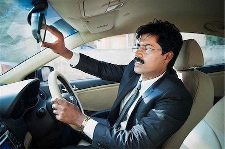 espejo retrovisor - South Indian businessman adjusting the rear view mirror of a car Foto de stock - Sin royalties Premium, Código: 630-06724908