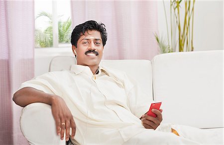 smiling indian mustache - South Indian man listening to a mp3 player Stock Photo - Premium Royalty-Free, Code: 630-06724933