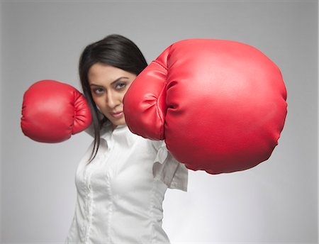 Businesswoman punching with boxing gloves Foto de stock - Sin royalties Premium, Código: 630-06722011