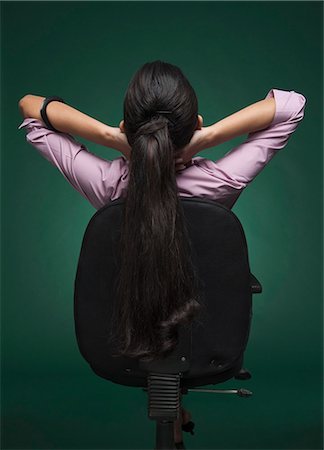 Rear view of a businesswoman sitting on a chair with her hands behind head Stock Photo - Premium Royalty-Free, Code: 630-06722050