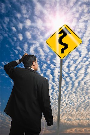 puzzled - Businessman looking at a Zig Zag Road sign Stock Photo - Premium Royalty-Free, Code: 630-06722192