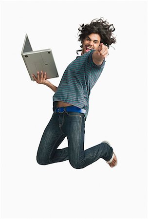 simsearch:630-06722257,k - Man jumping while using a laptop Foto de stock - Royalty Free Premium, Número: 630-06722290