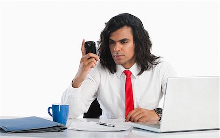 simsearch:6108-06166081,k - Businessman reading text message on a mobile phone at the desk Stock Photo - Premium Royalty-Free, Code: 630-06722292