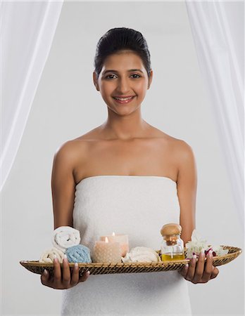 Woman holding a tray of spa products and smiling Stock Photo - Premium Royalty-Free, Code: 630-06722497