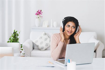 Woman listening to headphones in front of a laptop Stock Photo - Premium Royalty-Free, Code: 630-06722519