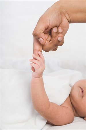 son and daughter lying in the bed - Baby holding finger of mother Stock Photo - Premium Royalty-Free, Code: 630-06722571