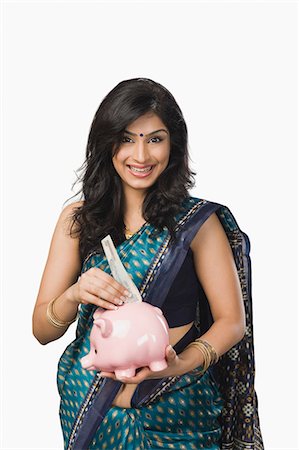 people depositing in the bank - Woman inserting money into a piggybank Stock Photo - Premium Royalty-Free, Code: 630-06722607