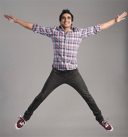 south asian teen boy - Portrait of a man jumping with his arm outstretched Stock Photo - Premium Royalty-Free, Code: 630-06722620