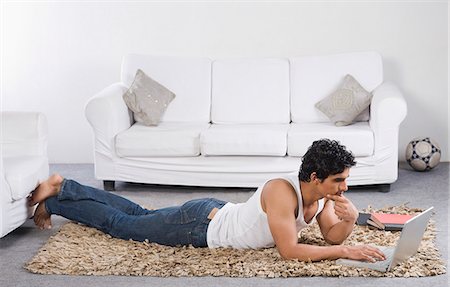 Man using a laptop on the floor Stock Photo - Premium Royalty-Free, Code: 630-06722634