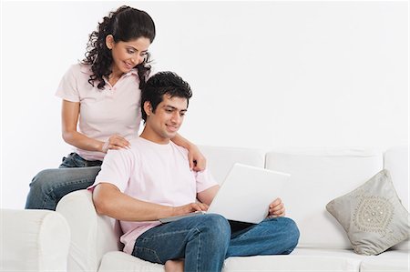 simsearch:630-06722744,k - Couple sitting in a couch and using a laptop Fotografie stock - Premium Royalty-Free, Codice: 630-06722744