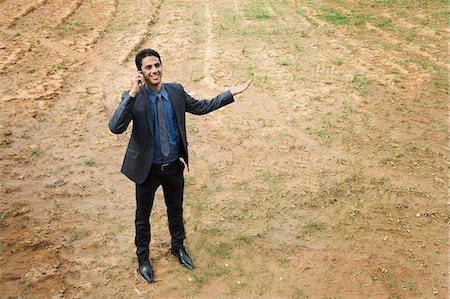 field alone smiling young man outdoors - Businessman talking on a mobile phone in a field Stock Photo - Premium Royalty-Free, Code: 630-06722926