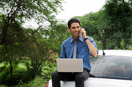 simsearch:630-06724909,k - Businessman using a laptop and a mobile phone while sitting on his car Photographie de stock - Premium Libres de Droits, Code: 630-06722936